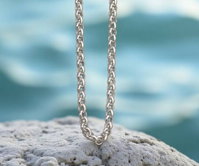 Italialainen sterling 925 -hopeaketju valkoisella rantakivellä, taustalla sinertävä meri.