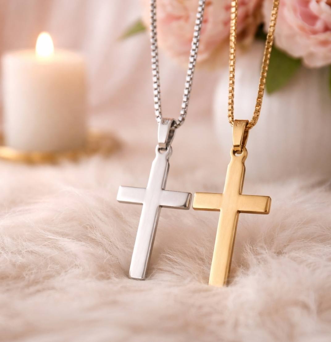 Hopeinen ja kultainen ristiriipus kaulaketjussa rippilahjaksi pehmeällä alustalla kynttilän ja kukkien edessä