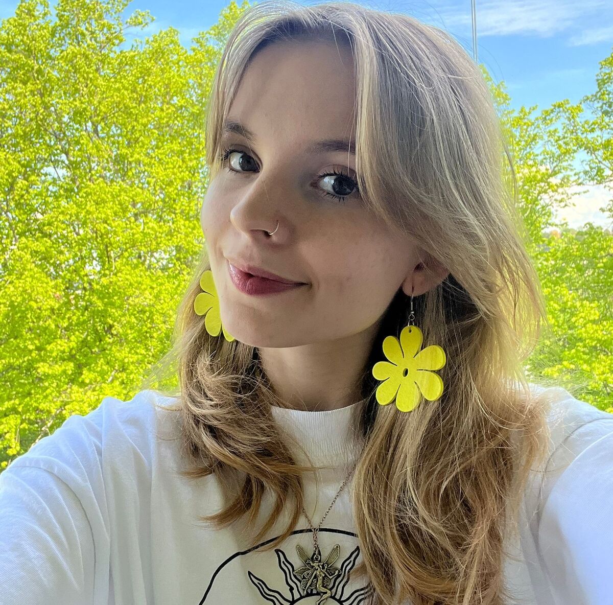 Keltakukkaiset 5cm puiset UNIKKO korvakorut mallin korvissa kesäisessä maisemassa