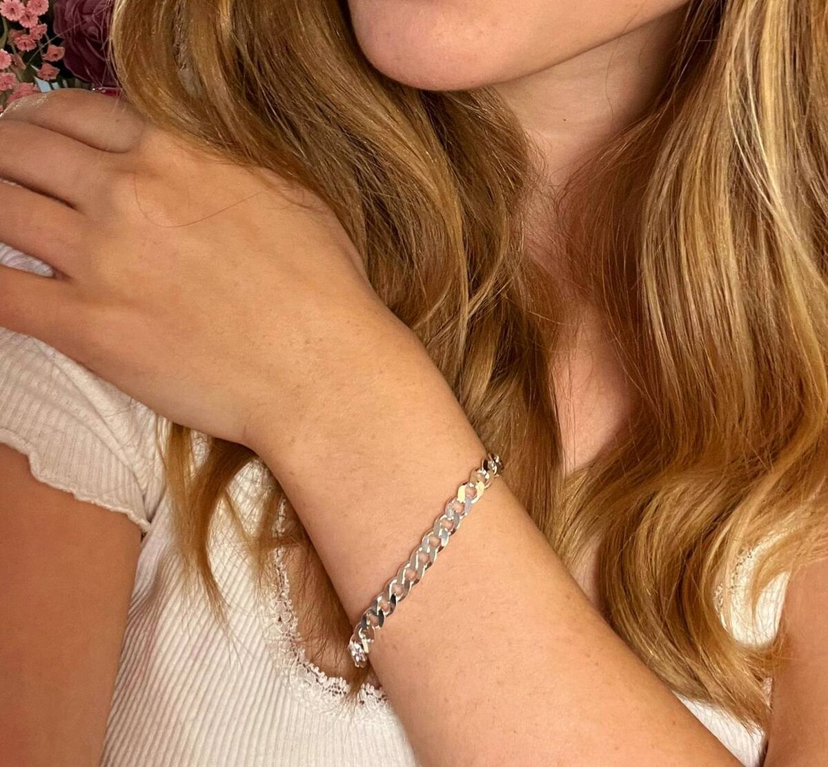 Hopeinen 5,8 mm panssarirannekoru suomalaisen kultasepän käsityönä. Naisen ranteessa oleva rannekoru hohtaa kauniisti valoa vasten.