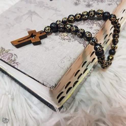 Musta luterilainen rukousnauha kultaisilla ristikoristeisilla helmillä ja puinen krusifiksi Raamatun päällä.
