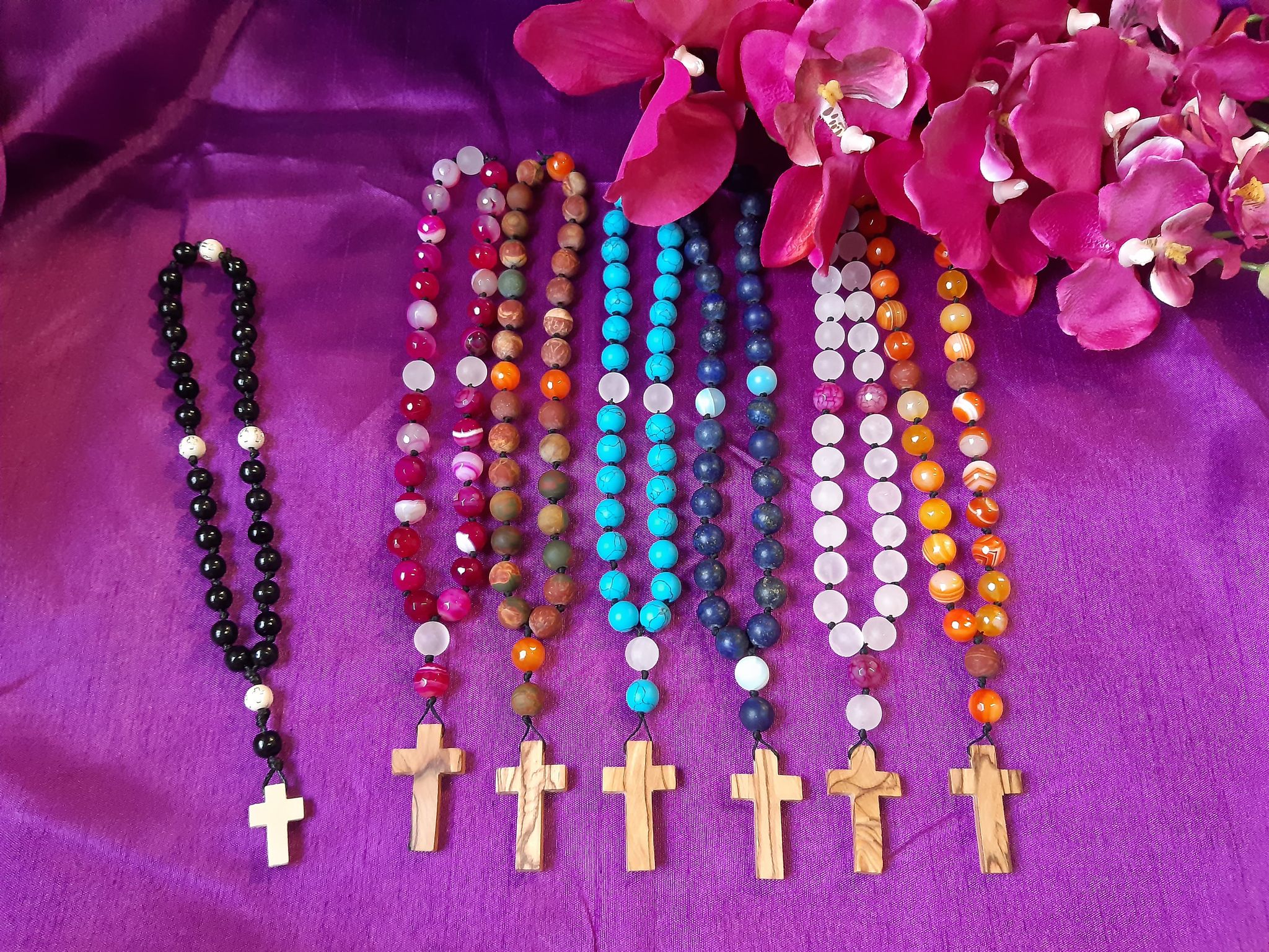 Kivihelmistä valmistettuja rukousnauhoja, joissa israelilalinen oliivipuuristi Israelista, aseteltuna vierekkäin violetille kankaalle
