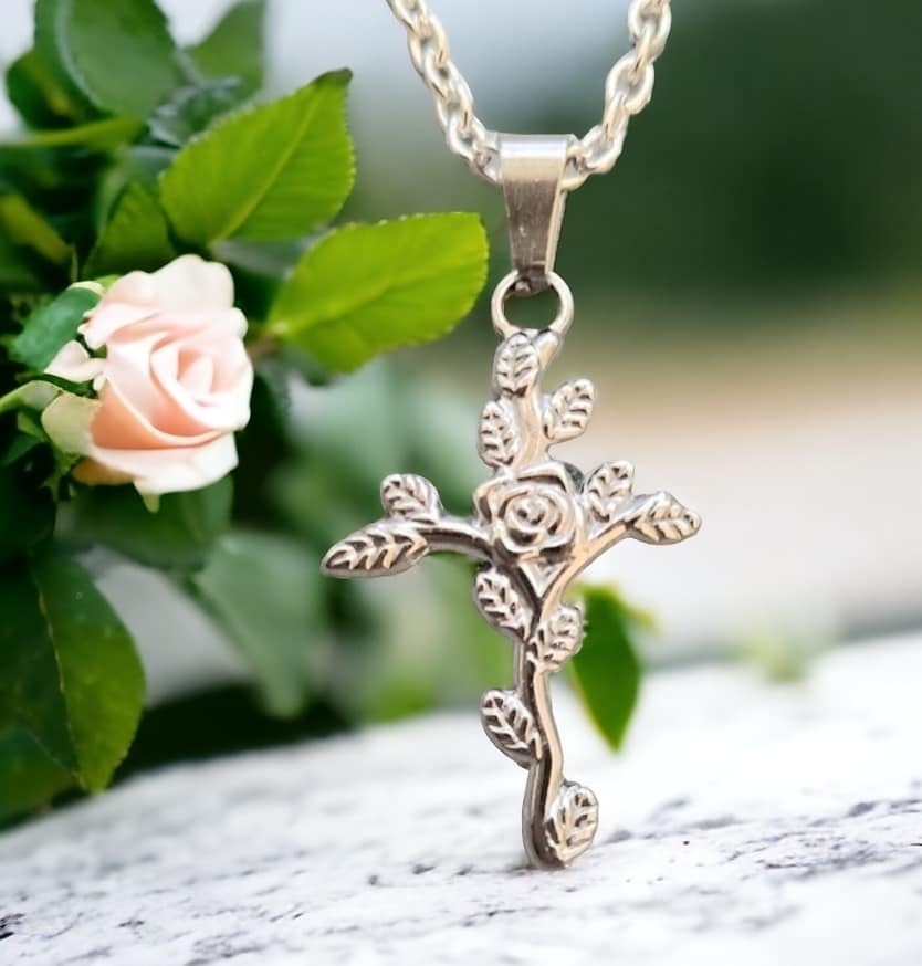 Teräksinen ruusuristi-kaulakoru, jossa risti muodostuu kauniisti kietoutuvasta ruususta ja sen lehdistä.