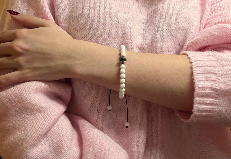 Valkoinen ristirannekoru mallin ranteessa